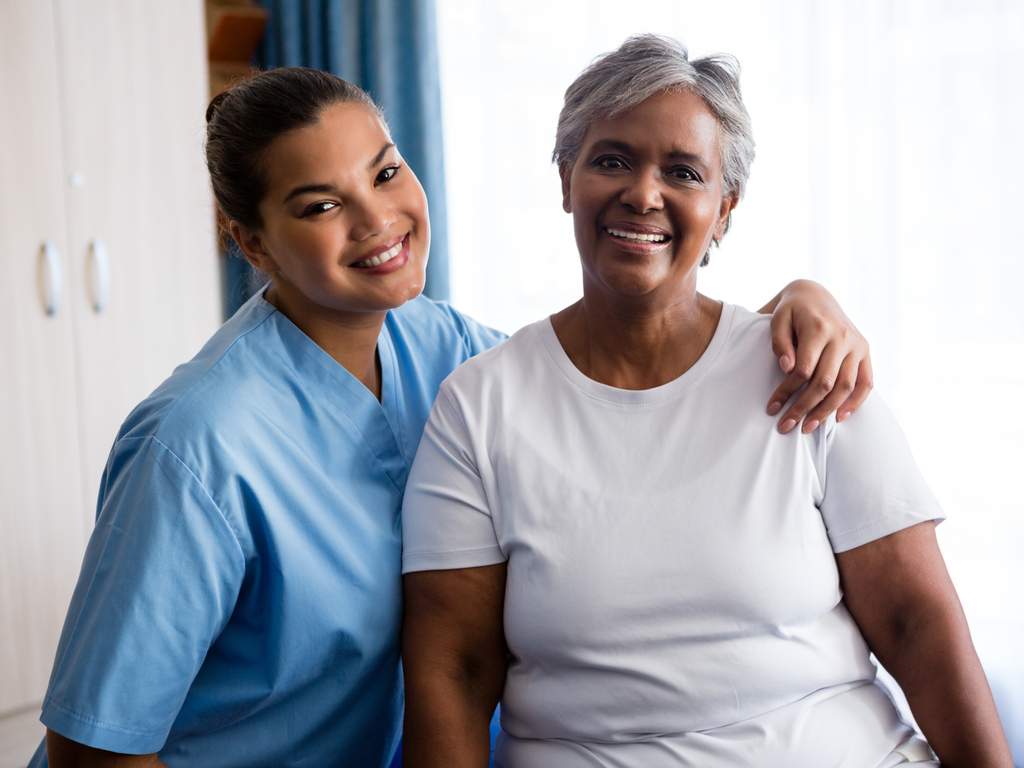 Caregiver smiling with an older woman at home Caregiver smiling with an older woman at home