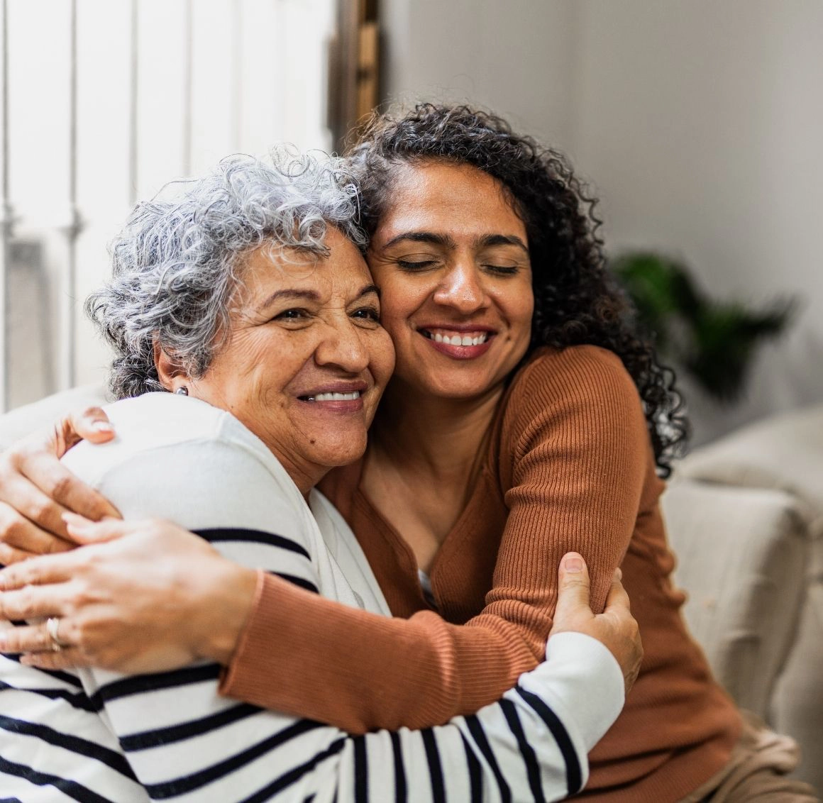 Caregiver hugging an older woman at home Caregiver hugging an older woman at home